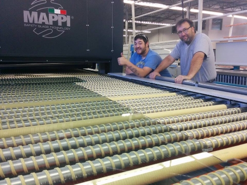 Michael Mckinney, co-owner of DT Glass posing next to the new furnace with a Mappi engineer