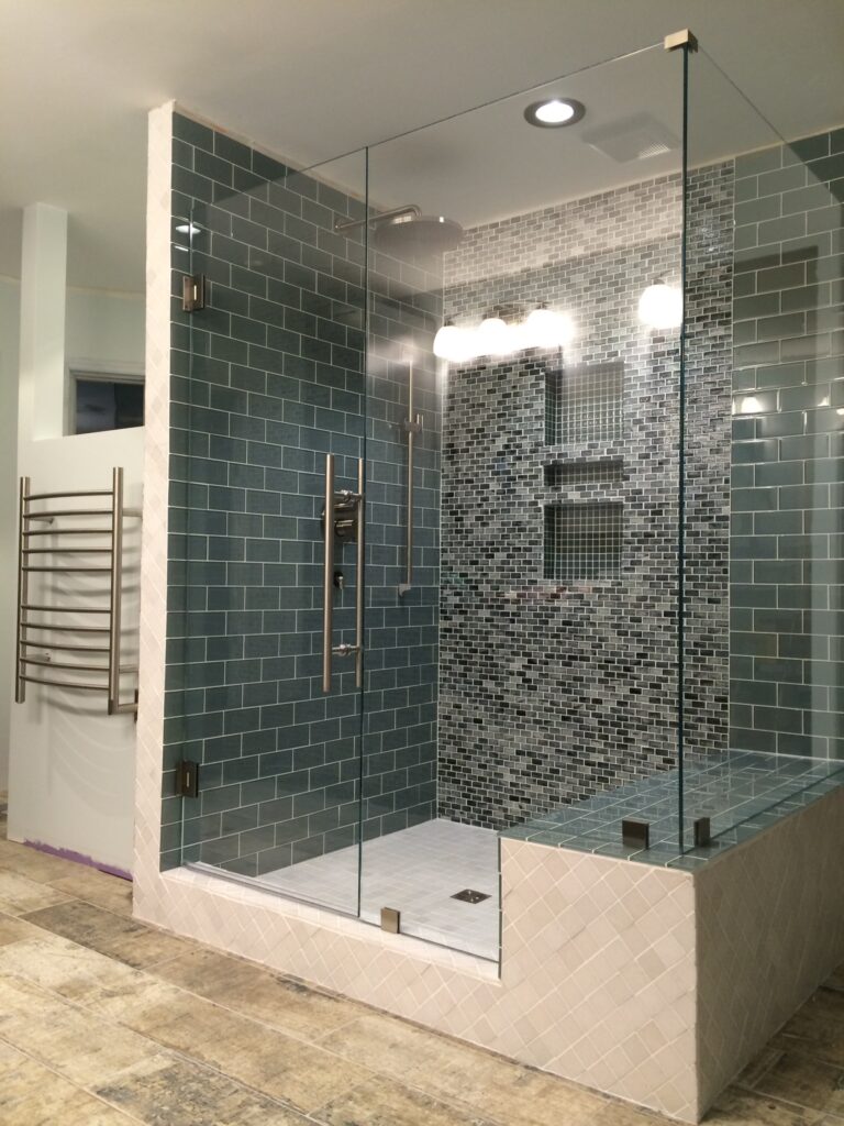 a shower in the corner of the room with a door, a panel, a 90 degree corner, and another panel attached to the wall