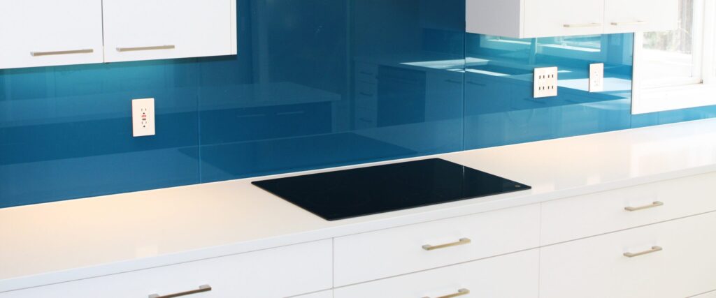 a kitchen counter and stove with blue backpainted glass backsplash