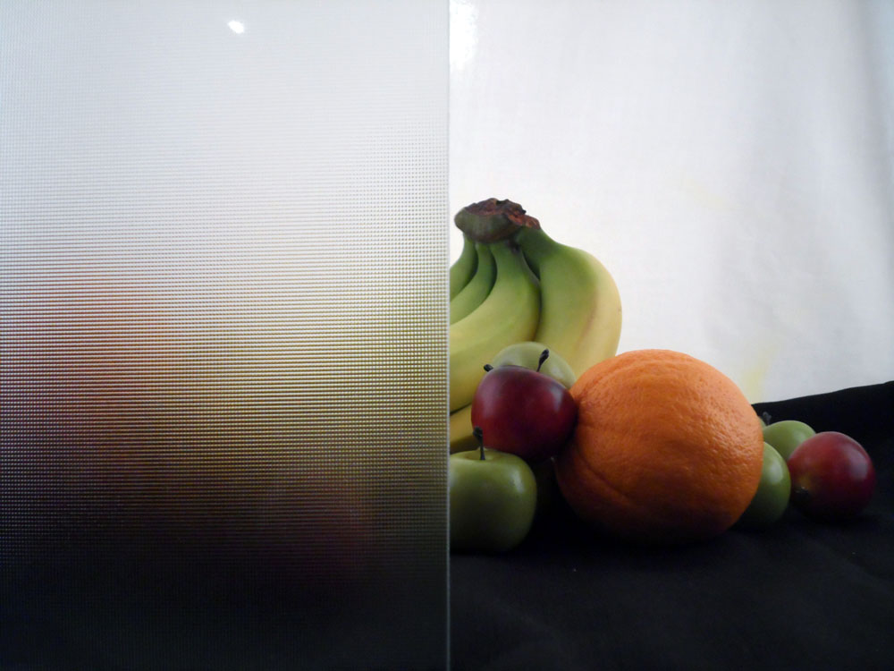 a glass display with some fruit half covered by glass, the glass has many small tightly packed bubbles in a grid, the fruit is almost impossible to make out