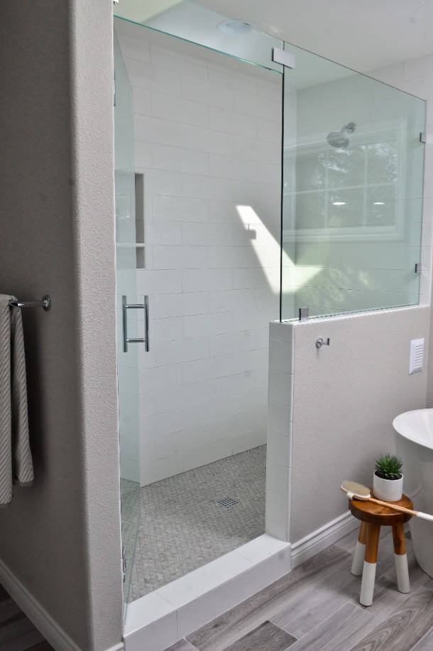 a shower with a glass transom above the door to support a panel