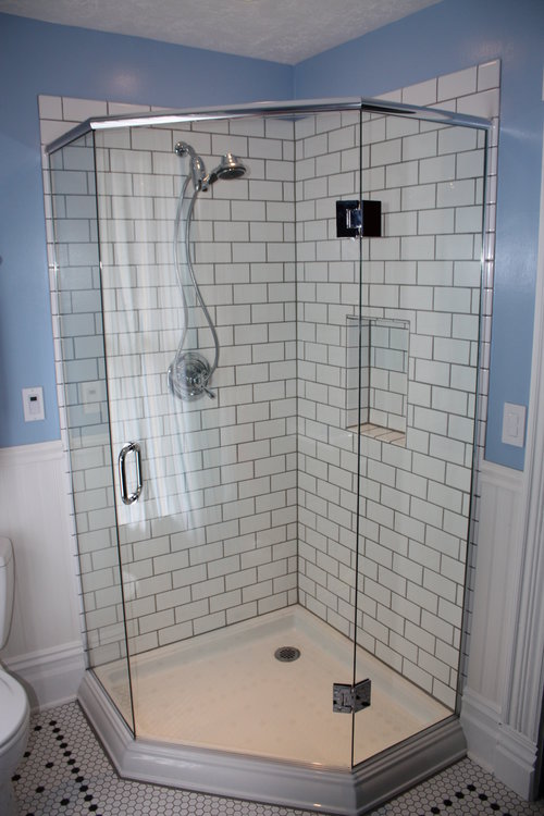 a shower in a corner with a panel, a 135 degree angle, a door, another 135 degree angle and a panel which makes the overall footprint of the shower smaller