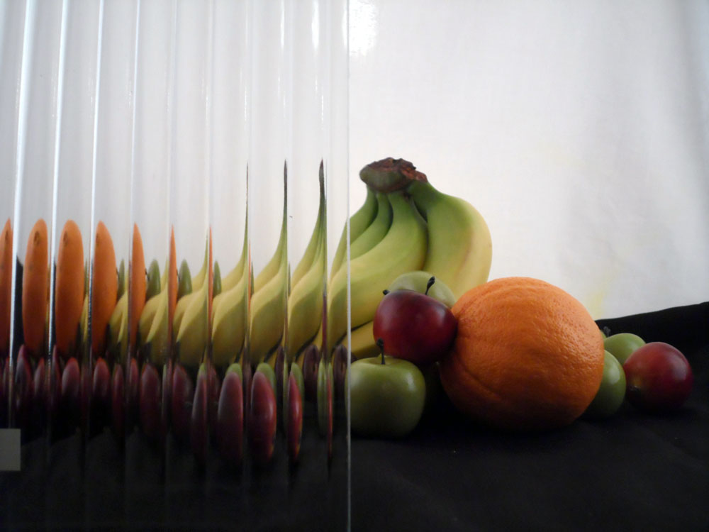 a glass display with some fruit half covered by glass, the glass has a series of vertical bumps cut into it, the fruit is fairly visible