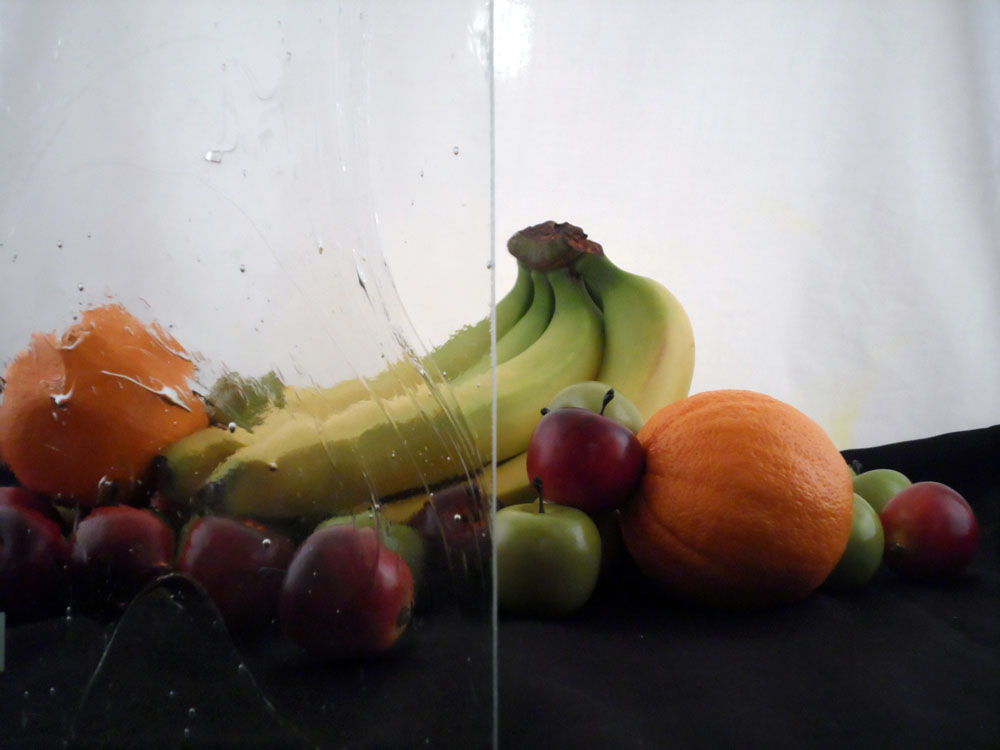 a glass display with some fruit half covered by glass, the glass is mostly clear but with a wavy streaky pattern molded into it